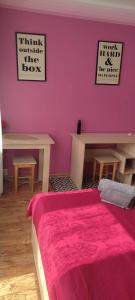a bedroom with a pink wall with a bed and benches at HOSTEL Róża in Suwałki