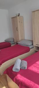 a room with three beds with red sheets and towels at HOSTEL Róża in Suwałki