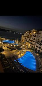 a large swimming pool with lounges and umbrellas at night at Apartment at Samarah Dead Sea Resort in Sowayma
