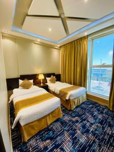 راحة للأجنحة الفندقية Comfort hotel suites في حائل: غرفة فندقية بسريرين ونافذة
