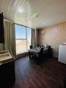 une salle à manger avec une table et une grande fenêtre dans l'établissement راحة للأجنحة الفندقية Comfort hotel suites, à Haïl