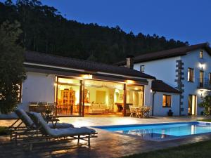 une maison avec une piscine en face d'une maison dans l'établissement Impresionante villa entre mar y montaña, à La Cavada