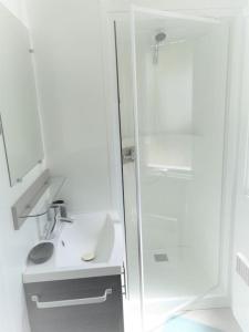 Un baño blanco con ducha y lavabo. en Coquillages & Crustacés avec Piscine Chauffée & Plage, en Marennes