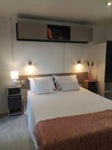 1 dormitorio con 1 cama blanca grande y 2 almohadas en Coquillages & Crustacés avec Piscine Chauffée & Plage, en Marennes