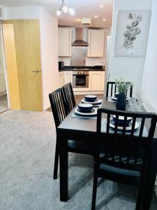 a kitchen with a table and two chairs and a dining room at Bright & Spacious Flat - Perfect for Exploring London , Slough & Windsor! in Slough