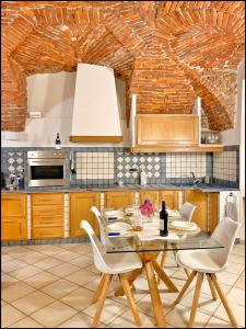 a kitchen with a table and chairs and a brick wall at La Fiaba: bilocale nel centro storico di Cuneo in Cuneo +13 photos