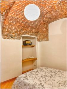 Un dormitorio con una pared de ladrillo y una cama en La Fiaba: bilocale nel centro storico di Cuneo en Cuneo