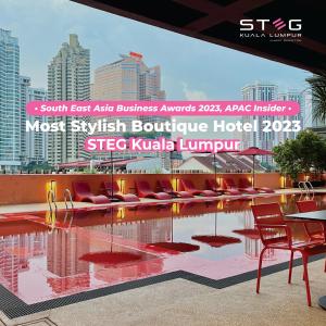 STEG Kuala Lumpur في كوالالمبور: فندق فيه مسبح والكراسي الحمراء والمباني