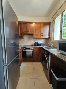 a kitchen with wooden cabinets and a stainless steel refrigerator at Villa Felix in Coral Bay