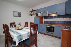 una cocina con armarios azules y una mesa con sillas en Apartmani Zec, en Šilo