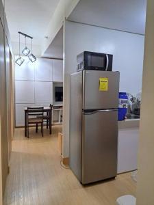 a stainless steel refrigerator in a kitchen with a table at Condo unit up to 10 pax - with Netflix and Boardgames in Manila