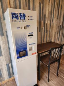 Un distributeur automatique est installé à côté d'une table en bois. dans l'établissement Cycle Guest House SHIOKAZE, à Setoda