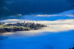 a large body of water with a town on a hill with clouds at Hotel Thuinerwaldele in Vipiteno