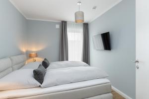 a white bedroom with a bed and a window at Sturmfrei Suite 8 in Scharbeutz