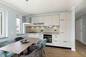 eine Küche mit weißen Schränken sowie einem Holztisch und Stühlen in der Unterkunft Sturmfrei Suite 8 in Scharbeutz