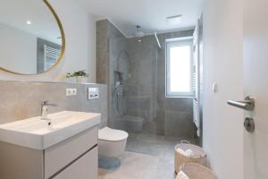 a bathroom with a sink and a toilet and a mirror at Sturmfrei Suite 8 in Scharbeutz +15 photos