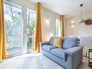 - un salon avec un canapé bleu et une grande fenêtre dans l'établissement La Palma Chic Apartment, à Cagliari
