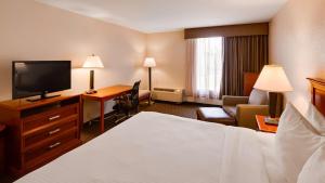Habitación de hotel con cama y escritorio con TV. en Best Western Tomah Hotel en Tomah