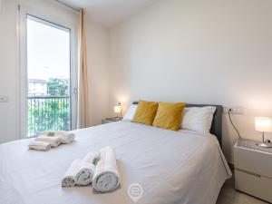 - une chambre avec un grand lit blanc et des serviettes dans l'établissement La Palma Chic Apartment, à Cagliari
