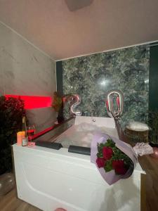 a bathroom with a tub with a bouquet of roses at Jacuzzi Apartment in Baia Mare
