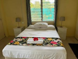 a bedroom with a large bed with a flower blanket at Libby's Vacation Rental 2 Bed Home 1-4 Guests in Nadi