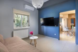 a blue room with a bed and a table and a tv at Queen Electra with pool and tennis court in Alikianós