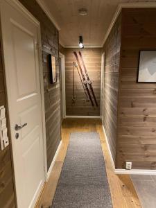 um corredor com paredes de madeira, uma porta e esquis em Hytte på fjellet em Håra