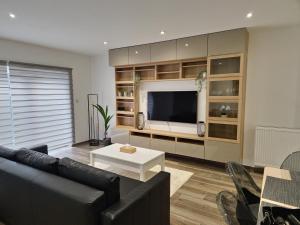 uma sala de estar com um sofá e uma televisão em le coin douillet em Saint-Ghislain