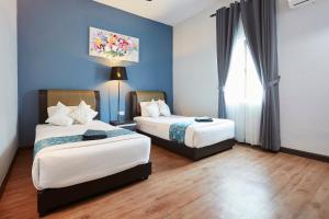D' Qamar Guesthouse في كُوانتان: سريرين في غرفة بجدران زرقاء وأرضيات خشبية