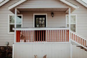 Ein weißes Haus mit einer Veranda mit orangefarbenem Geländer in der Unterkunft The Shasta Cottage in Klamath Falls