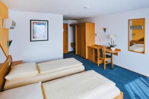 a hotel room with two beds and a desk at Hotel Central in Weil am Rhein