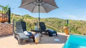 eine Terrasse mit Stühlen und einem Sonnenschirm neben einem Pool in der Unterkunft Casa Tortela Almáchar by Ruralidays in Almáchar