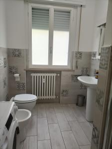 a bathroom with a toilet and a sink and a window at Residenza Chiara in Forlì