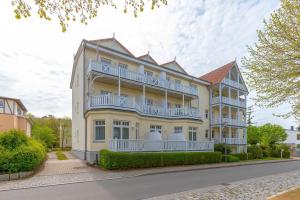 a large white building with balconies on a street at Villa-Parkblick-Wohnung-26-541 in Kühlungsborn
