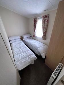 a small room with two beds and a window at E11 Sunnymede Ingoldmells Lee's holiday homes in Skegness