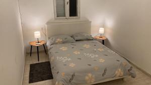 ein kleines Schlafzimmer mit einem Bett und zwei Tischen in der Unterkunft Прекрасная квартира на берегу Средиземного моря in Qiryat H̱ayyim
