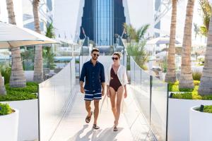 a man and woman walking down a walkway at a resort at Jumeirah Burj Al Arab Dubai in Dubai