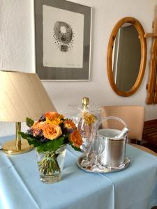 un jarrón de flores sobre una mesa con un espejo en Hotel Sommerhaus Garni am See, en Bodman-Ludwigshafen