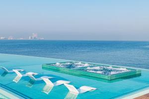 a swimming pool with white chairs and the ocean at Burj Al Arab Jumeirah in Dubai