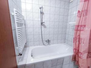 y baño blanco con bañera y ducha. en Ildiko Apartmanhaz, en Zamárdi