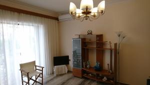 a living room with a television and a chandelier at Sunny family apartment in Chania close to the sea in Chania