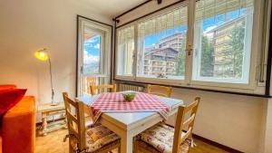 een tafel en stoelen in een kamer met ramen bij Appartamento Palace - Affitti Brevi Italia in Sauze d'Oulx