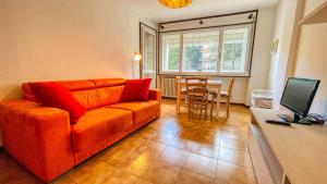 een woonkamer met een oranje bank en een tafel bij Appartamento Palace - Affitti Brevi Italia in Sauze d'Oulx