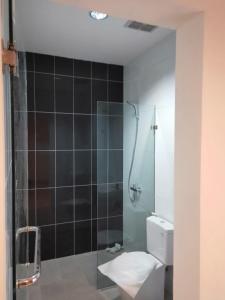 a bathroom with a glass shower with a toilet at The Holiday Guest House in Tanjungpandan