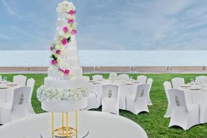 a white wedding cake with flowers on a table at Jumeirah Burj Al Arab Dubai in Dubai