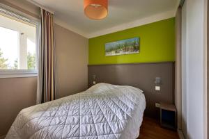 een slaapkamer met een bed en een groene muur bij L'Alouette - Appt en résidence avec terrasse in Courseulles-sur-Mer