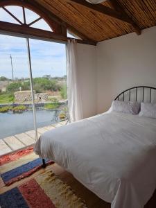 a bedroom with a bed and a large window at Aintree Lodge - Yoga Den in Langebaan