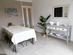 a white dining room with a table and a mirror at Maison familiale proche de la mer in Lancieux +9 photos