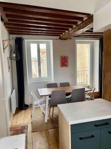 uma sala de jantar com mesa, cadeiras e janelas em La Petite Baleine, appt à 50m de la plage em Luc-sur-Mer