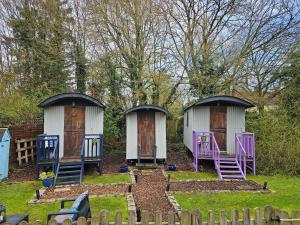 a group of three huts in a yard at Glamping At The Fox Inn Bramdean in Bramdean